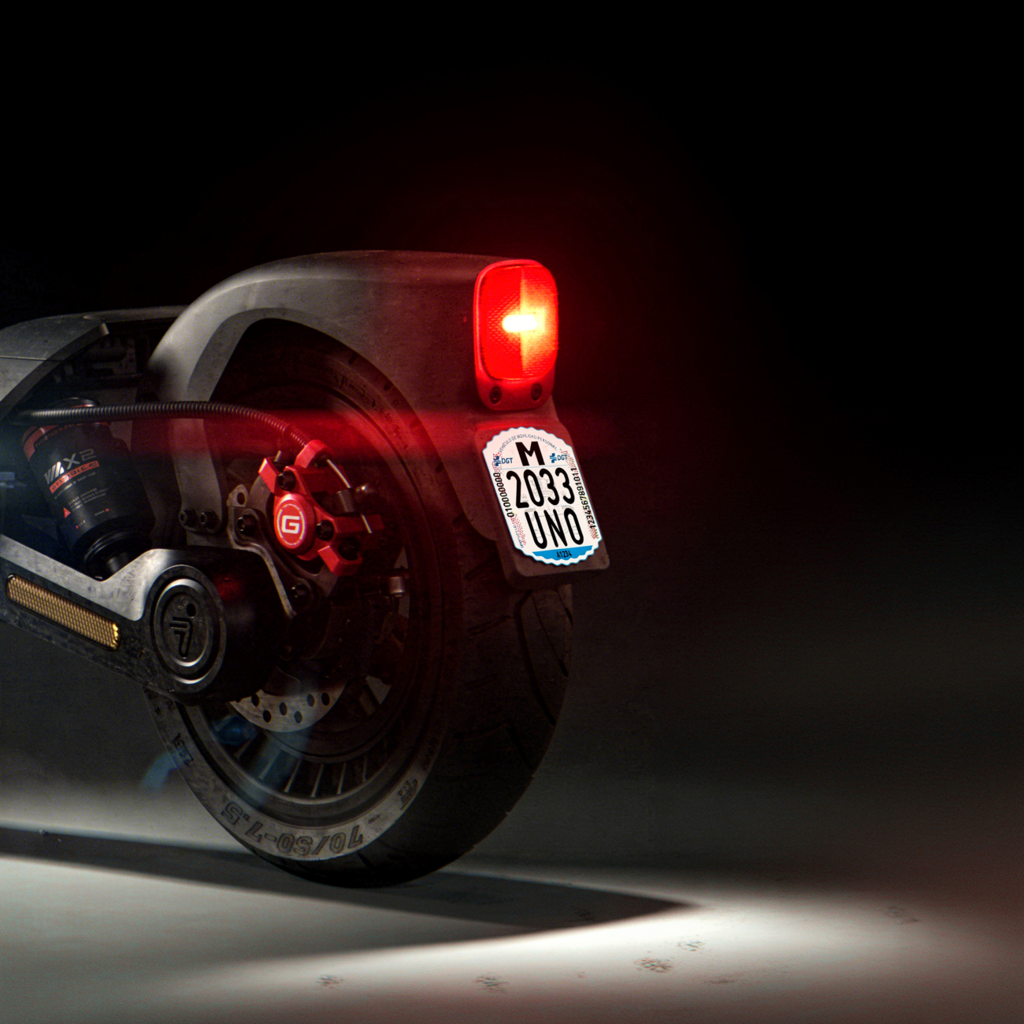 Matrícula VMP adhesiva DGT colocada en guardabarros trasero de patinete eléctrico con luz roja encendida